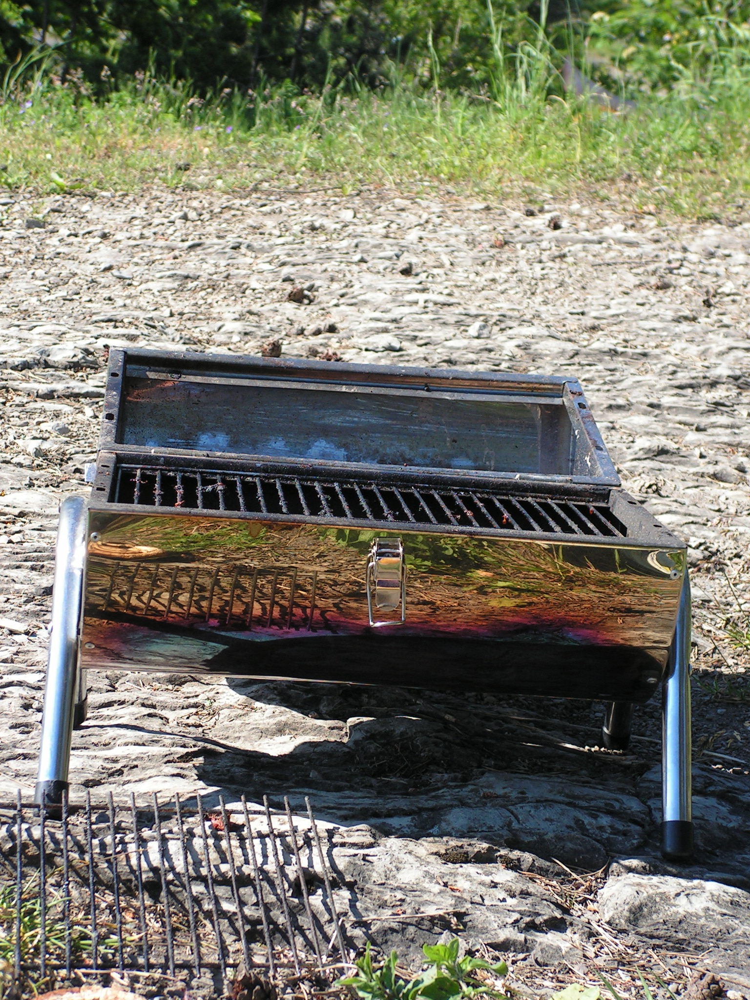 the grill is in dirt near a wooded area
