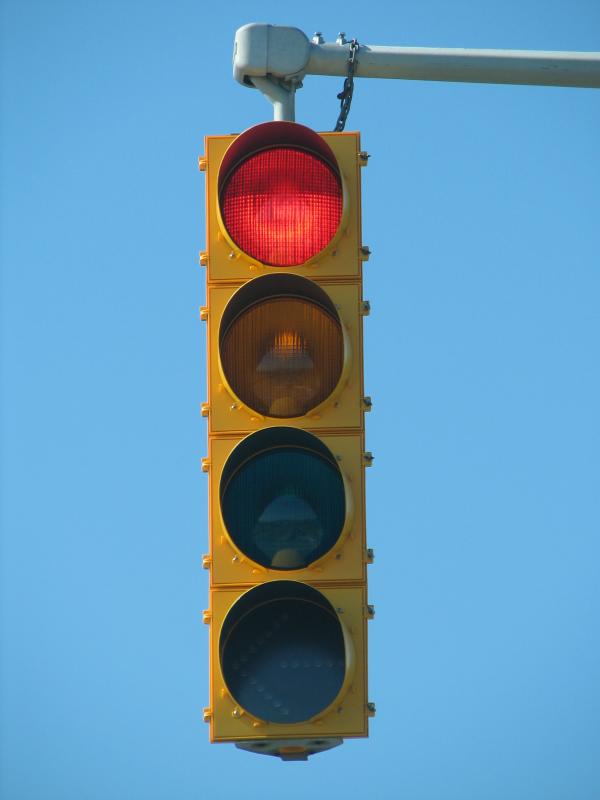 a traffic light showing red with a blue sky behind it