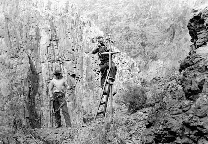 men climbing up the side of a cliff to gain their climb