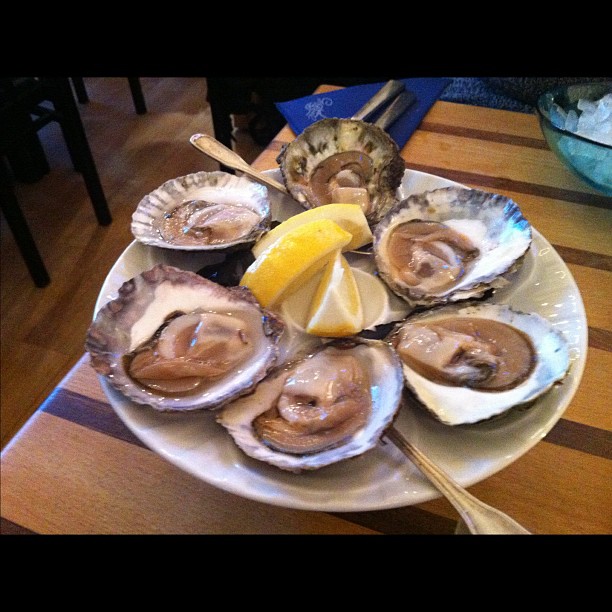 oysters are served on a plate with a lemon wedge and spoon