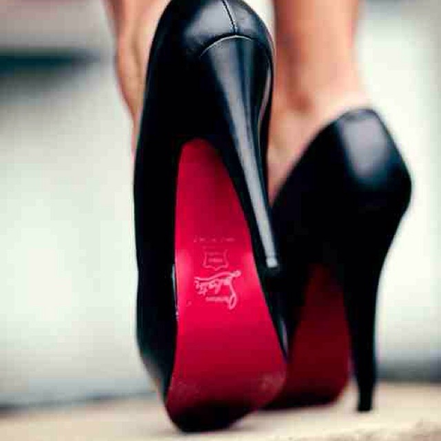 a person's black high heel shoes with red bottoms