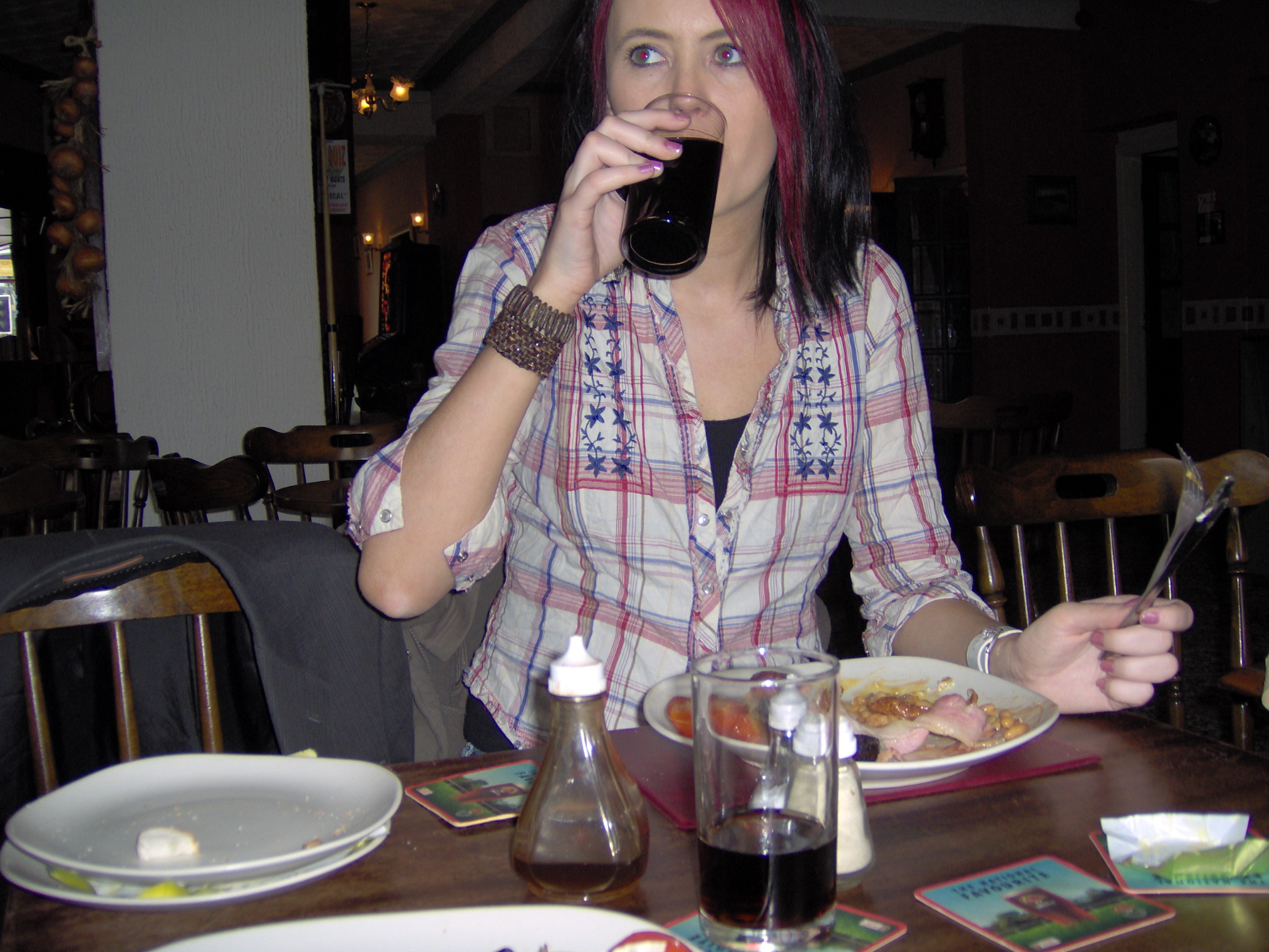 a woman sitting at a table drinking from a cup