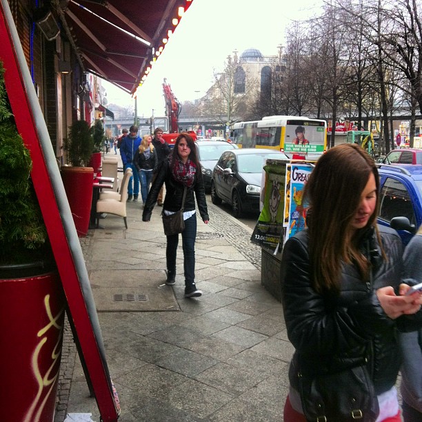 two s are on a busy street corner looking at their phones