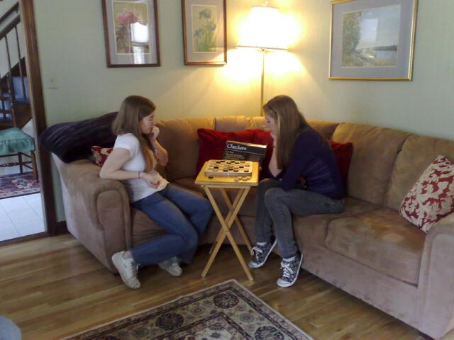 two women sit on couches and one sits on the end table