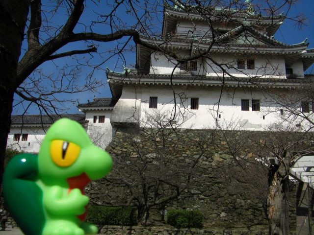 a statue in front of a castle, with trees and shrubs