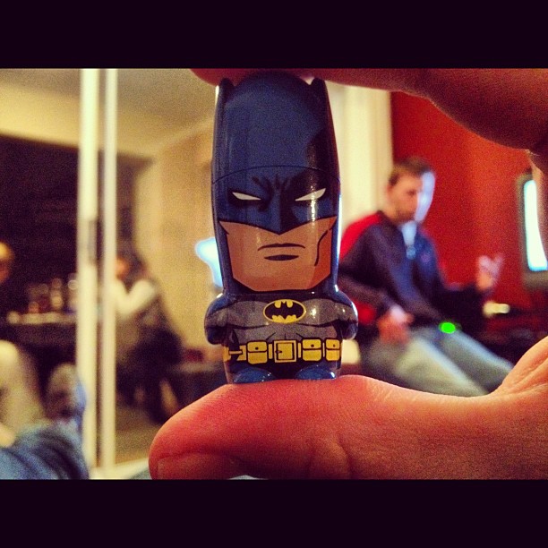 someone holding up a lego batman in front of a tv