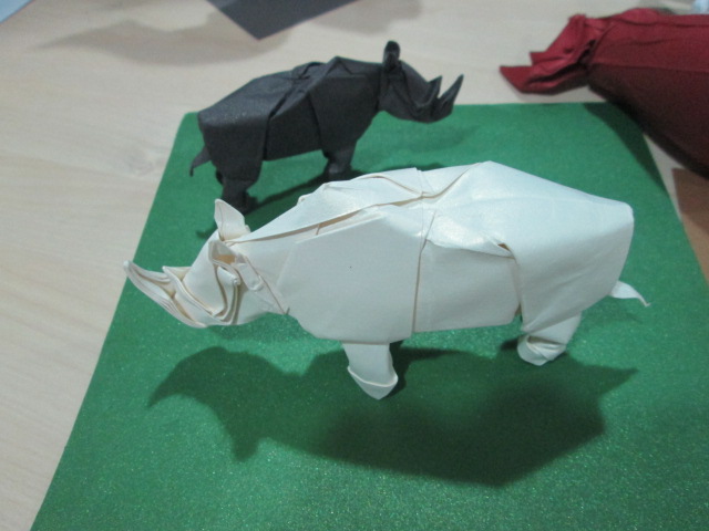 origami rhinoceros with folds in front of them sitting on green surface