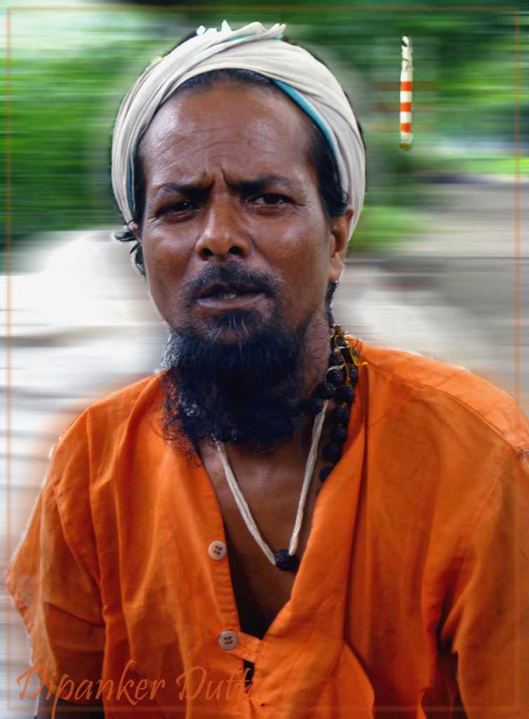 a man in orange with a turban on looking at the camera