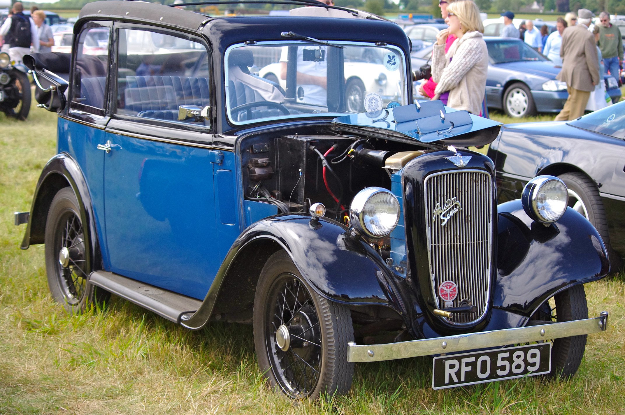 a classic blue car is parked in a field with other old cars