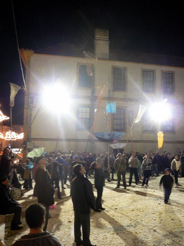 people standing in a courtyard at night holding flags