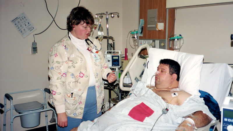 a woman standing next to a man in a hospital bed