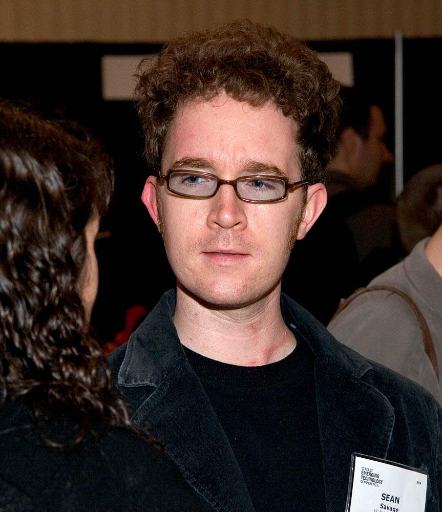 a man wearing glasses is looking at another man in a black shirt