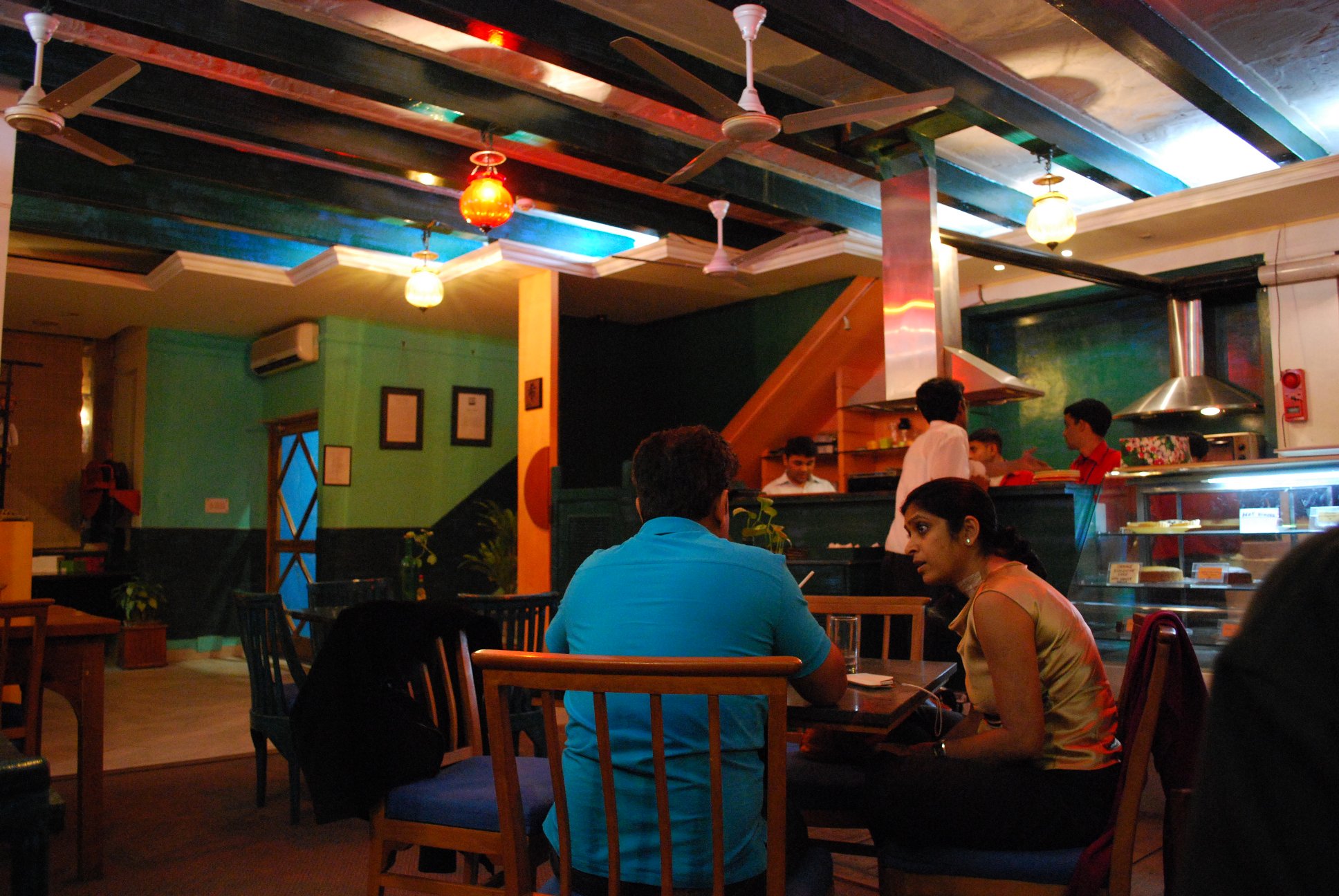 people in a restaurant with green walls and a counter