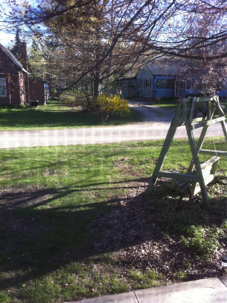 a wooden swing set next to a field in a suburban area