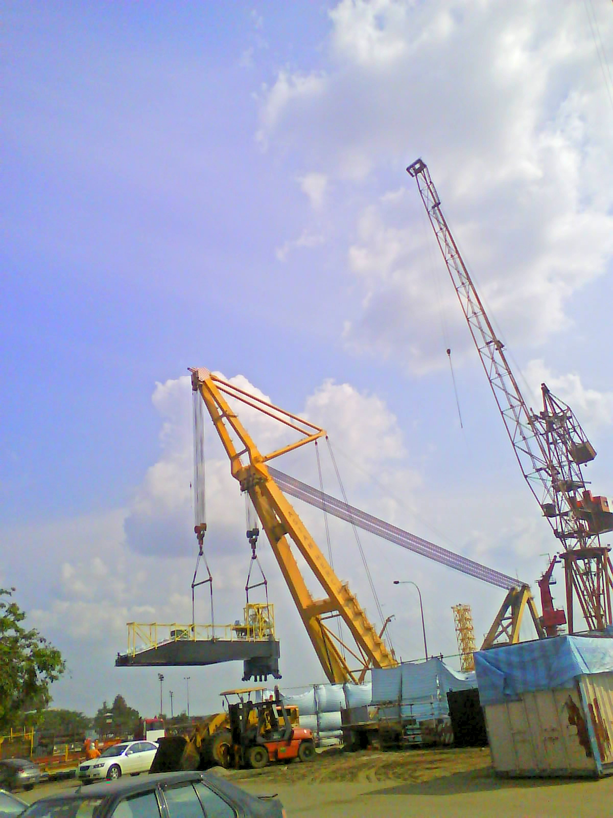 craned trucks are moving large containers with smaller ones on top