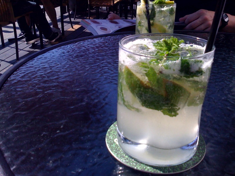 there are two cocktail glasses with ice and limes