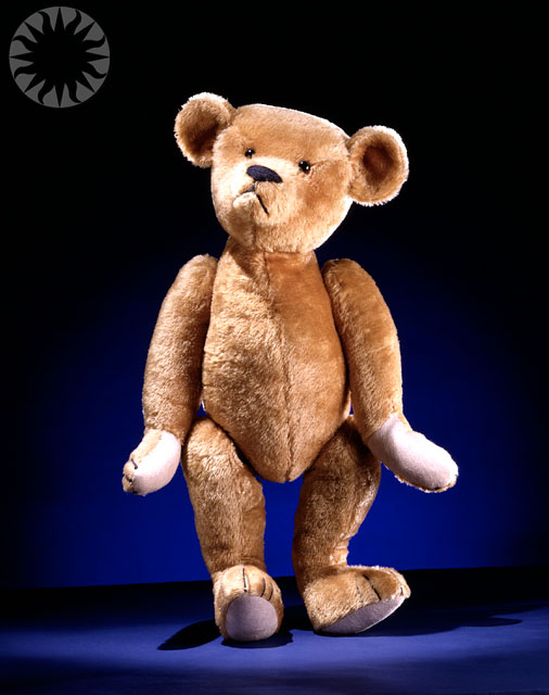 a brown teddy bear sitting on top of a blue background
