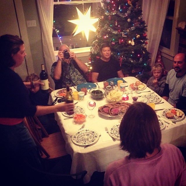 a family sitting around a table together during christmas time
