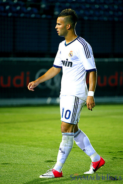 a male soccer player in a white uniform is walking