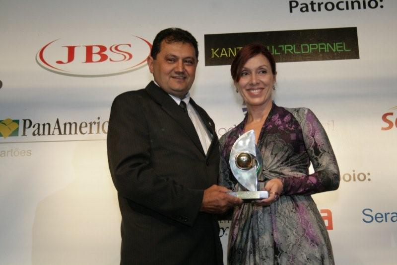 a man and a woman standing next to each other holding an award