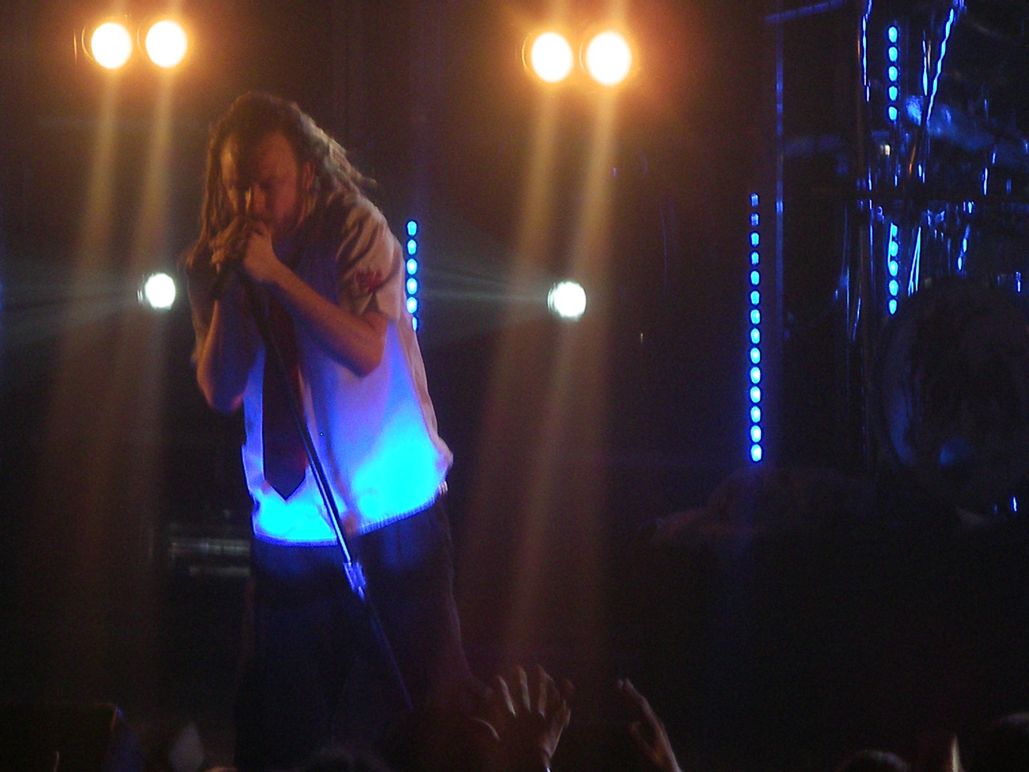 an asian male in concert clothes standing with his arm around the shoulder