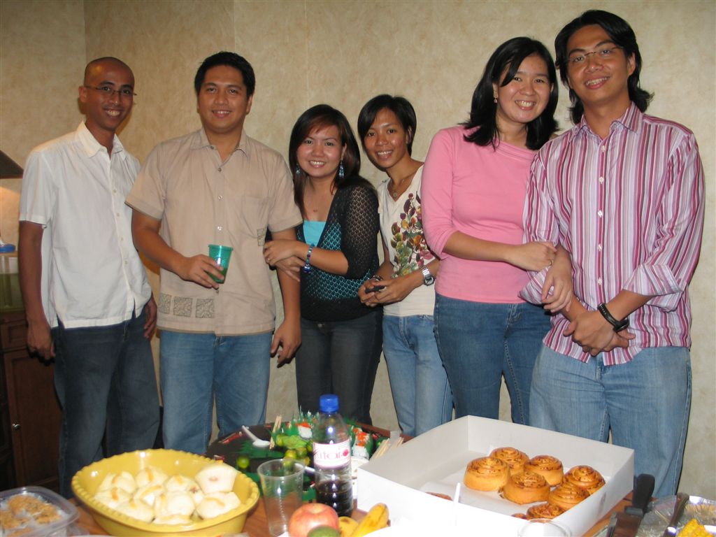 a group of people are posing together near a table with many snacks and drinks