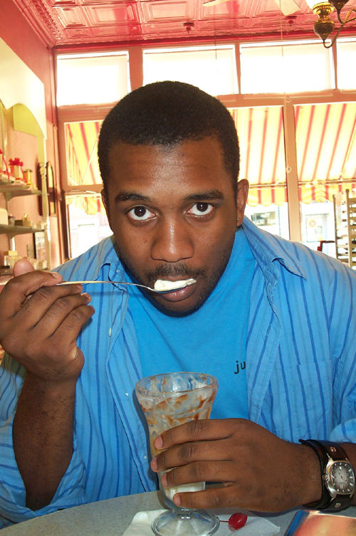 a man wearing blue and looking confused while holding onto a spoon