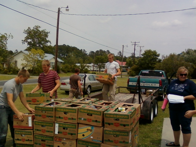 several people unloading boxes from the back of a truck