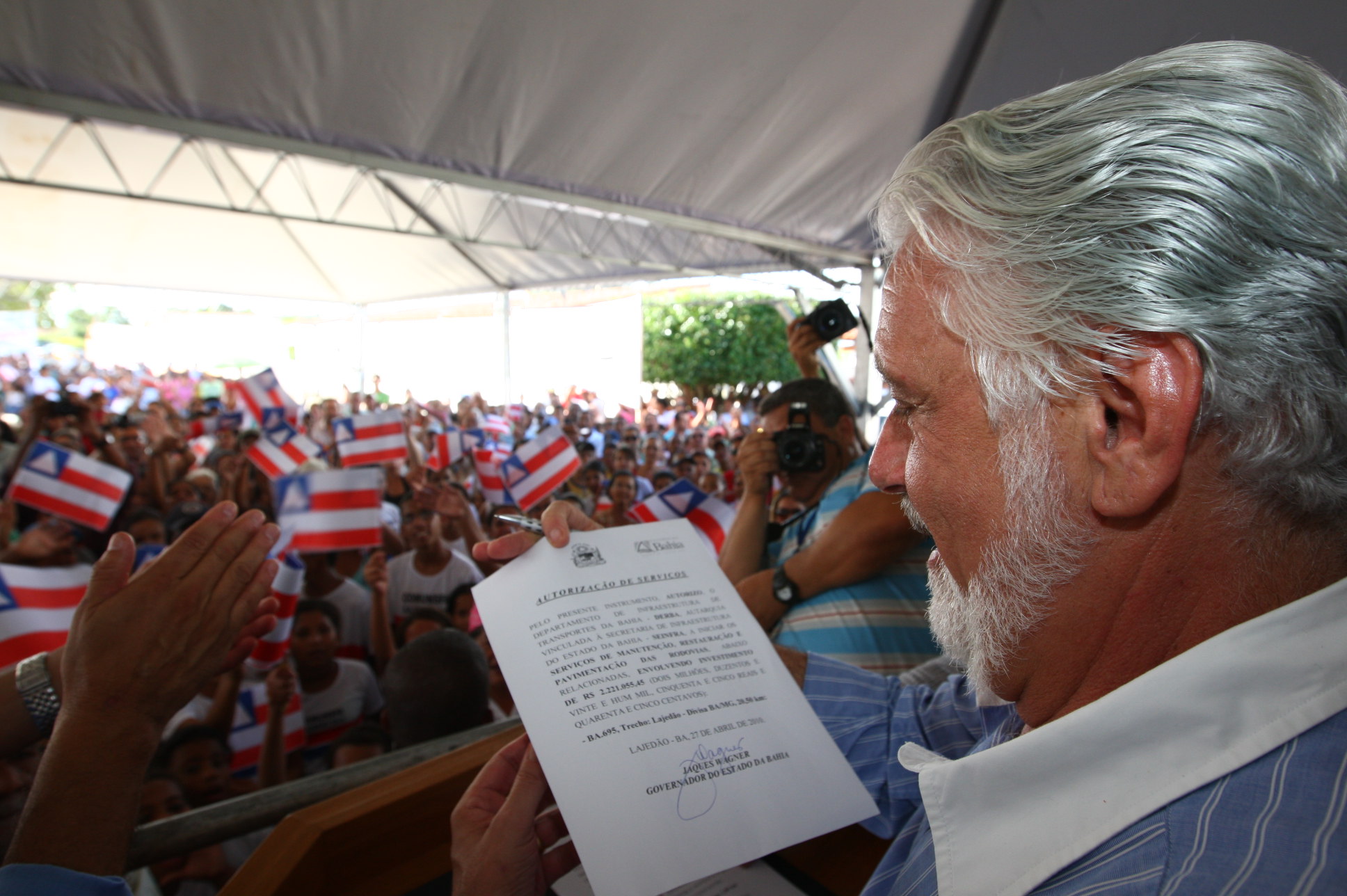 a man is holding a document with several people in the background