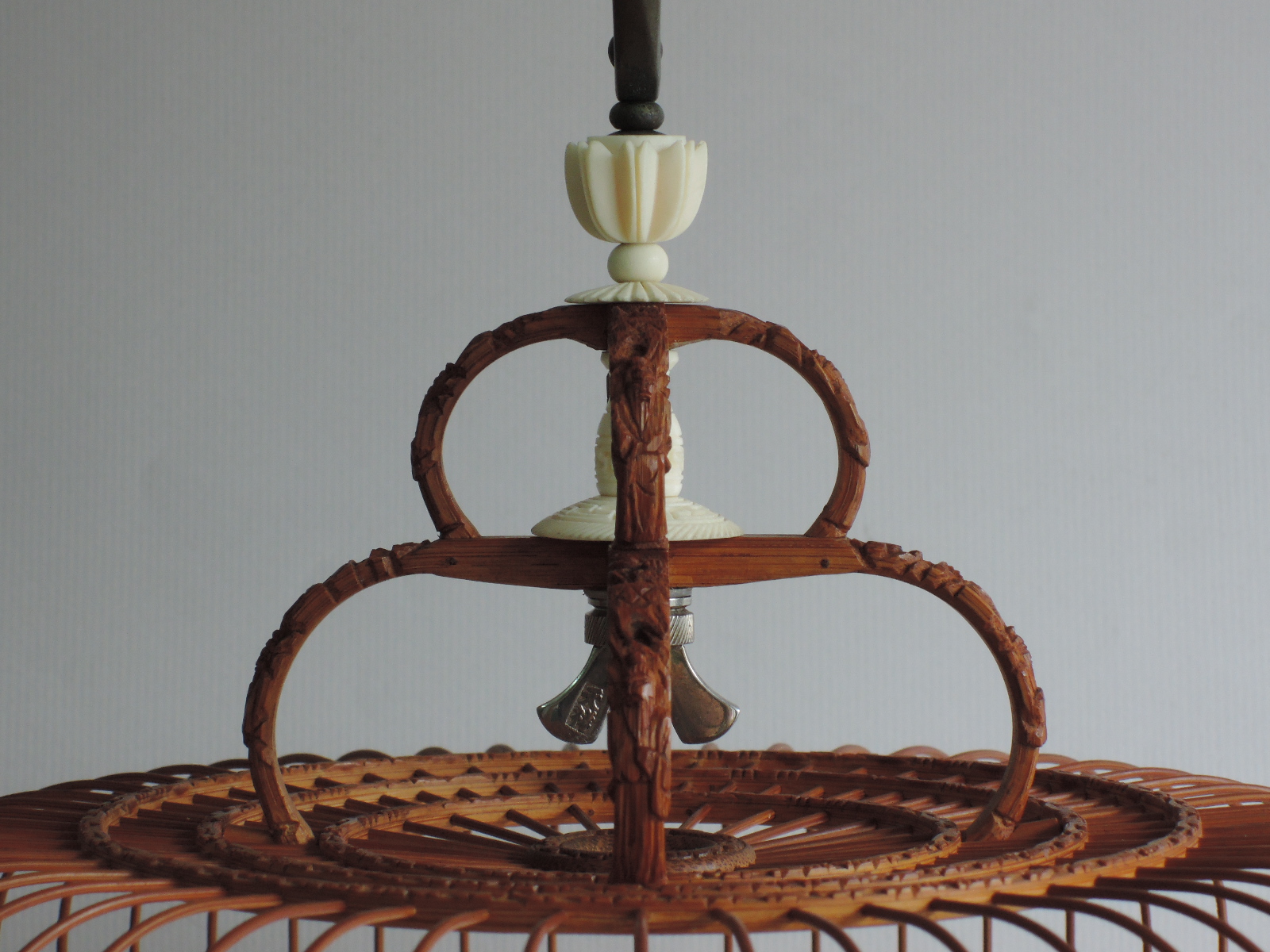 an ornate wicker chandelier hanging from a grey background