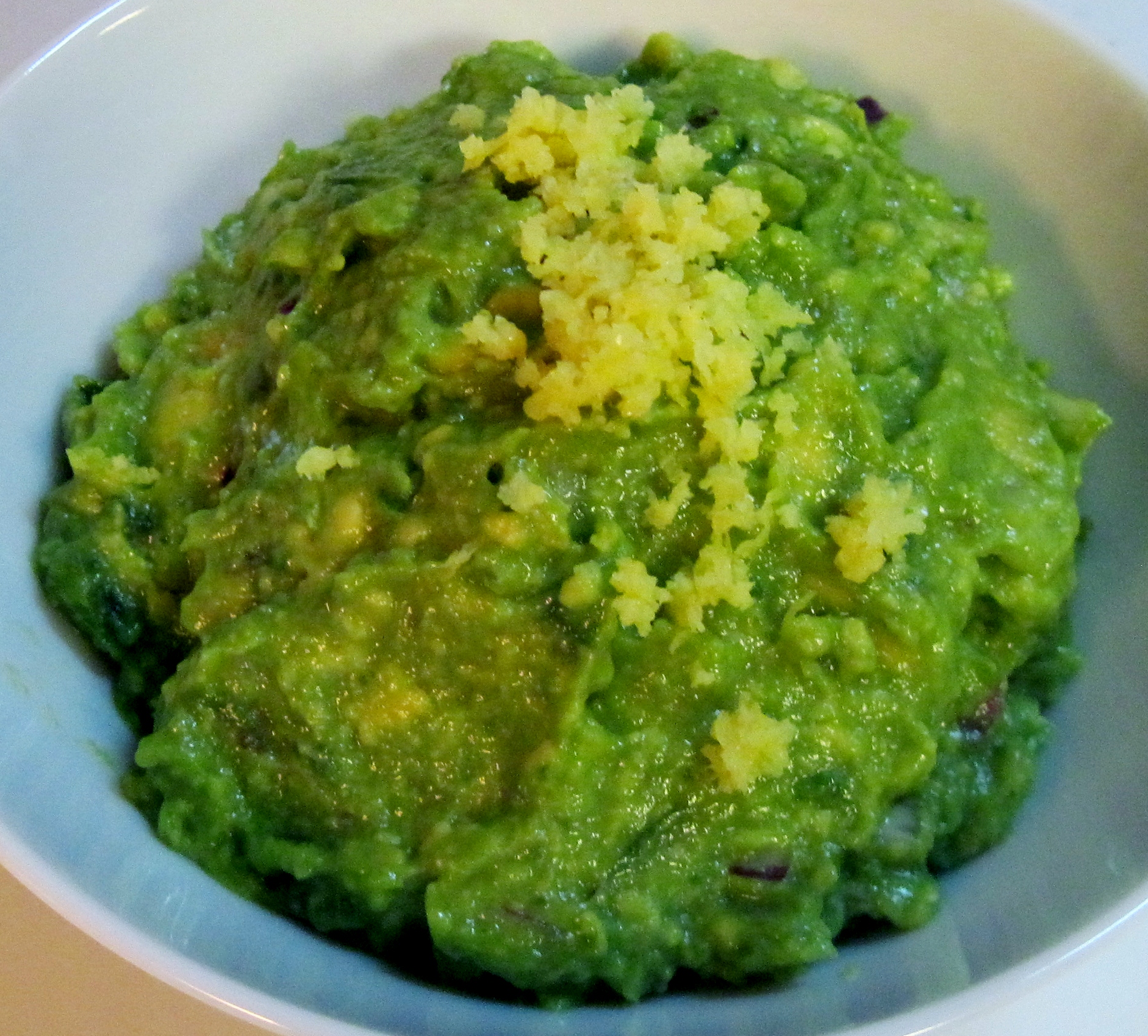 green guacamole in a bowl next to a spoon