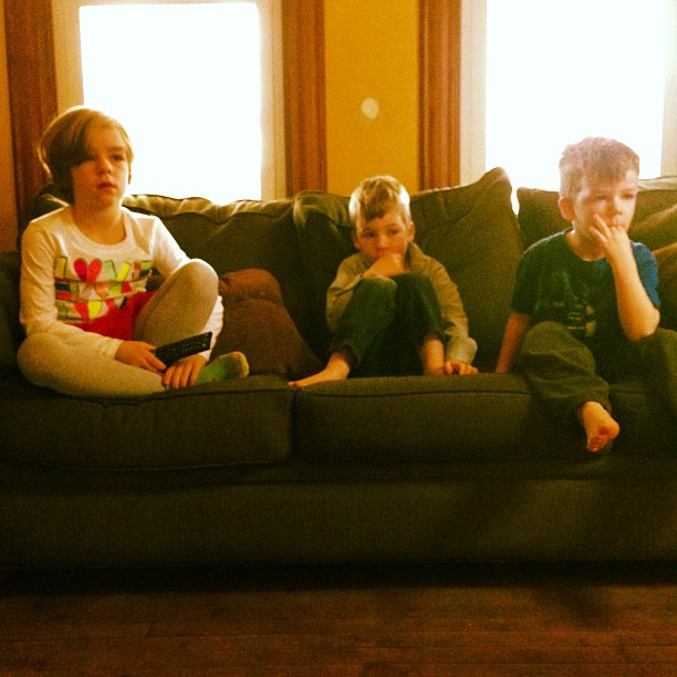 the three young children are sitting on a sofa