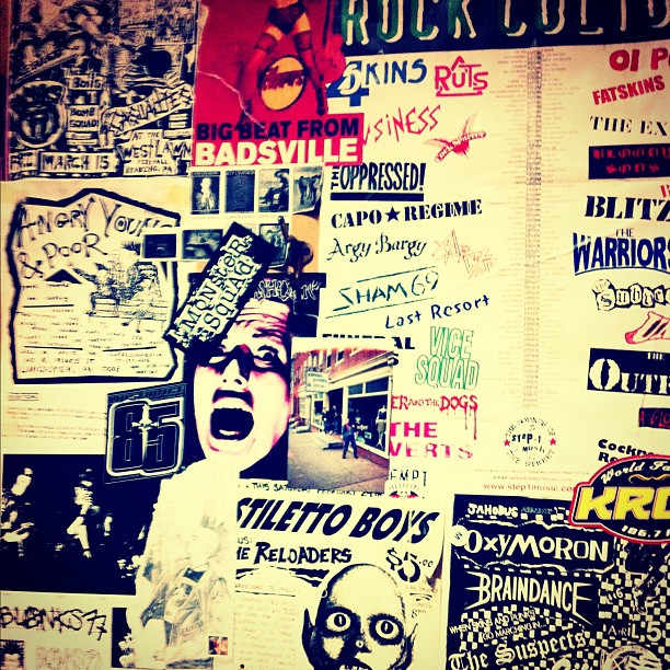 a wall covered with posters and graffiti, including one of a man's face