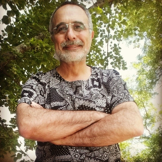 man with white beard and glasses standing with arms crossed