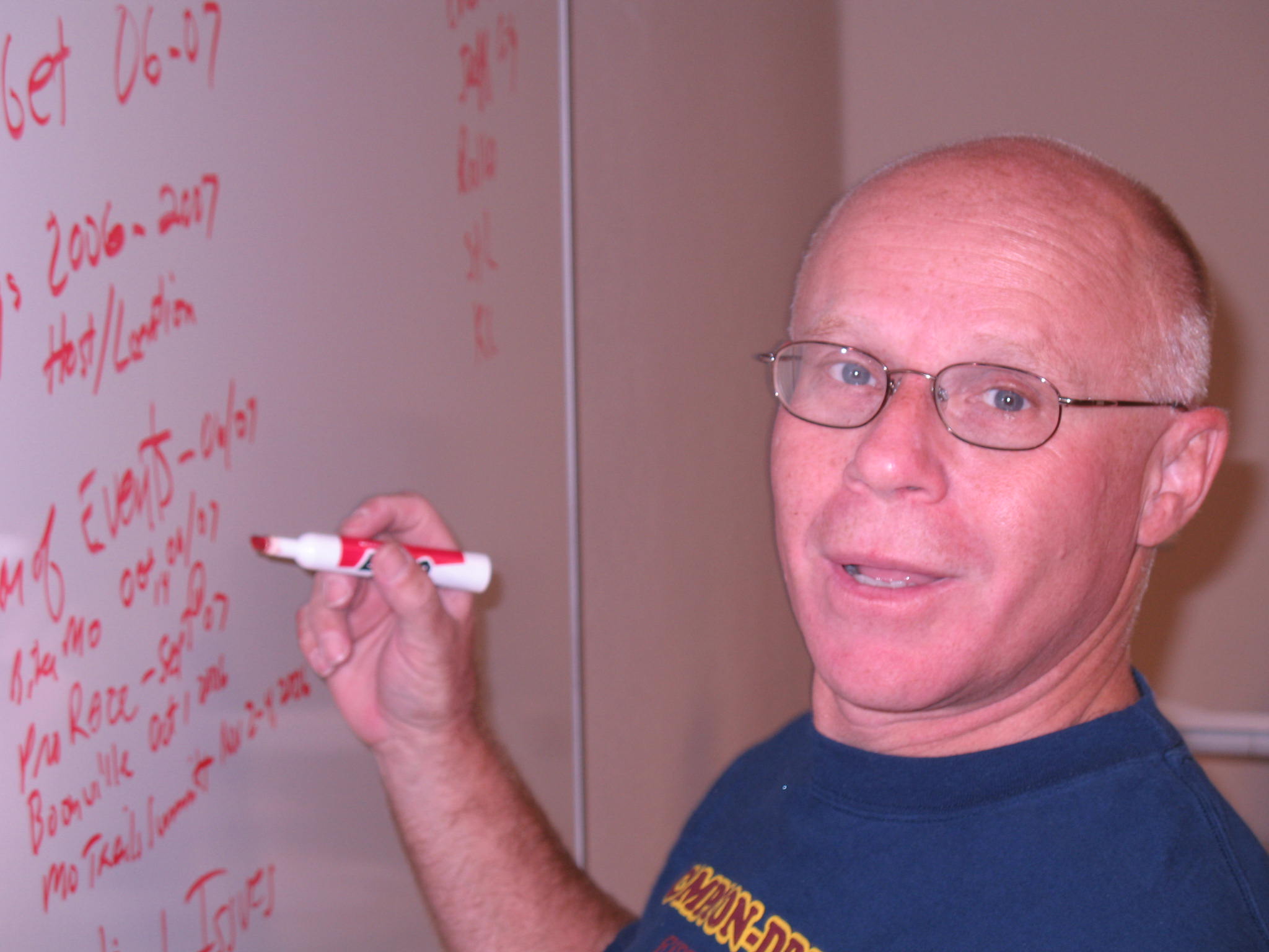 a man in blue shirt writing on a whiteboard