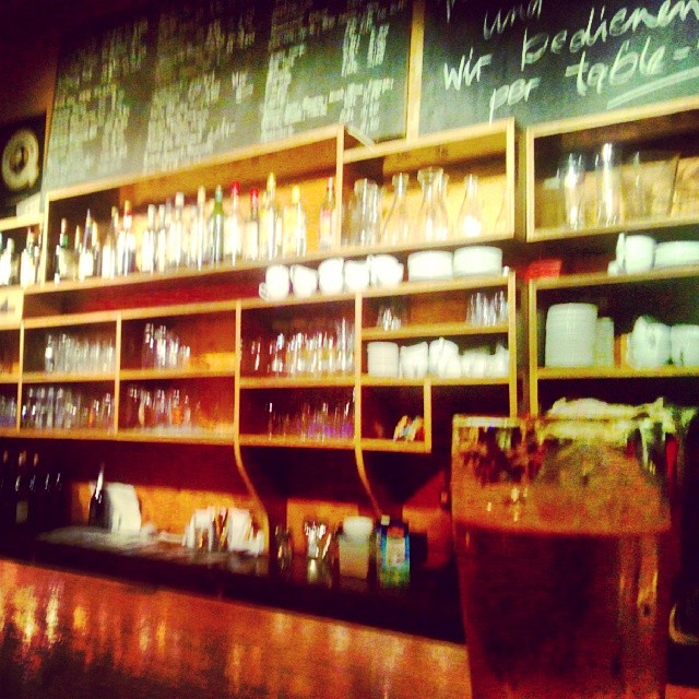 a very long bar has lots of glassware and shelves full of bottles