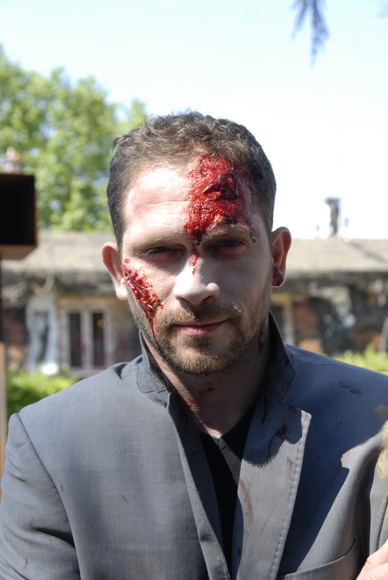 a man in costume standing in front of a house with paint all over his face