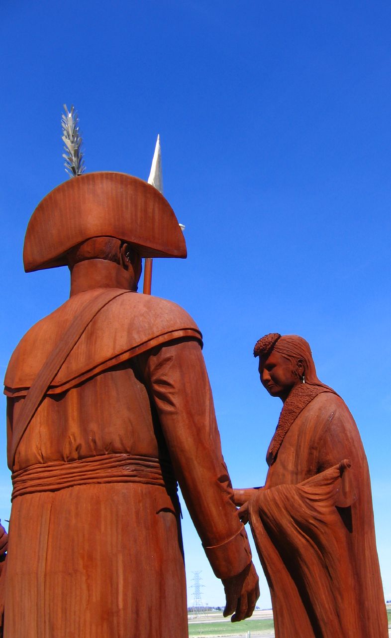 a wooden sculpture of a man holding the hand of a woman