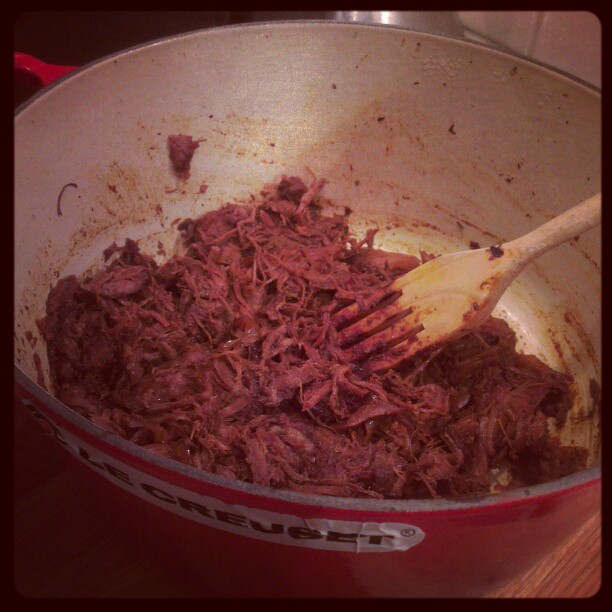 a bowl full of shredded meat and a wooden spatula