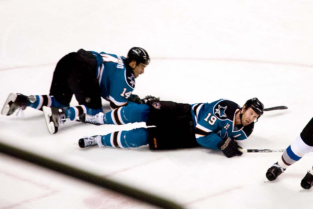 two men on a hockey field being tackled by one another