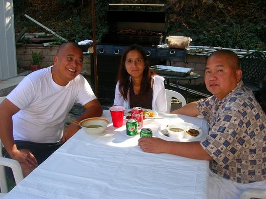 three people sitting at an outdoor table