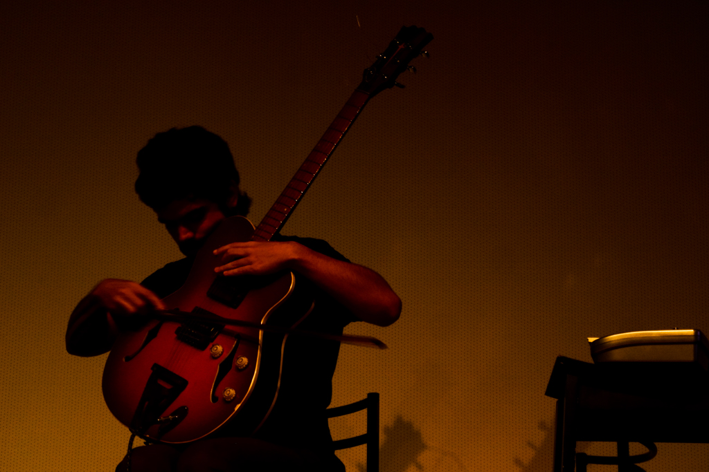 a man with his guitar behind him sitting down