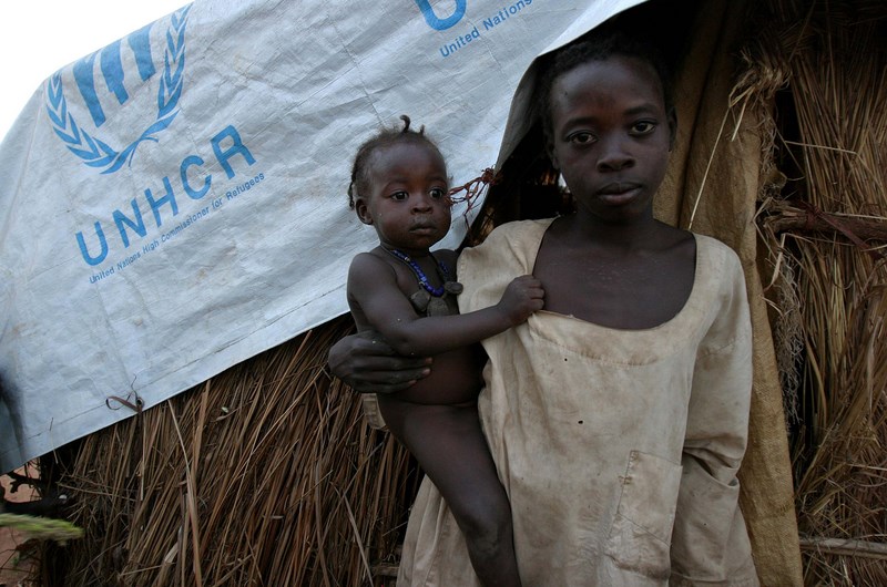 young children standing together near thatched roof