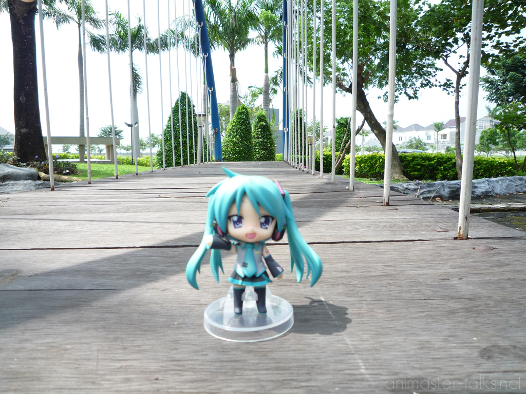 a doll is standing on a sidewalk and there is some trees and blue sky behind it
