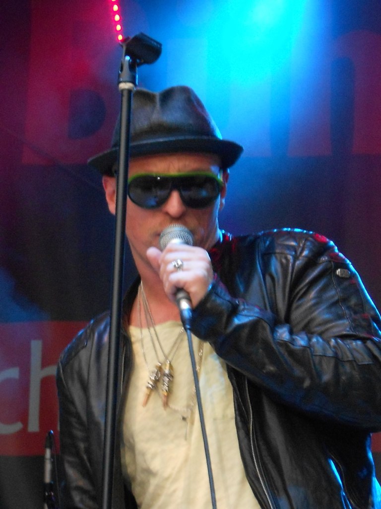 a man with glasses on his face singing in a microphone