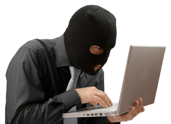 a masked man using his laptop with the screen closed