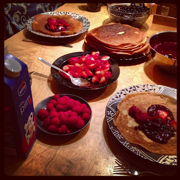 several plates with pancakes, berries and syrup