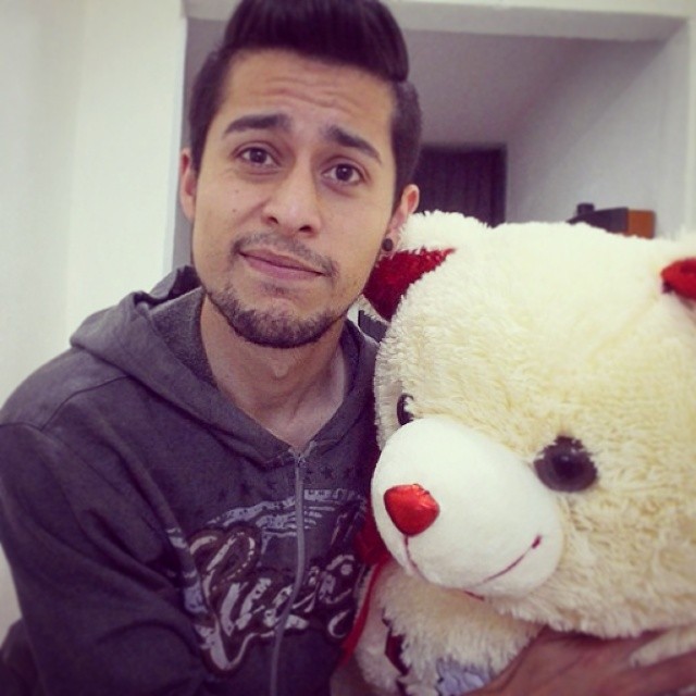 a man poses with a teddy bear in his home