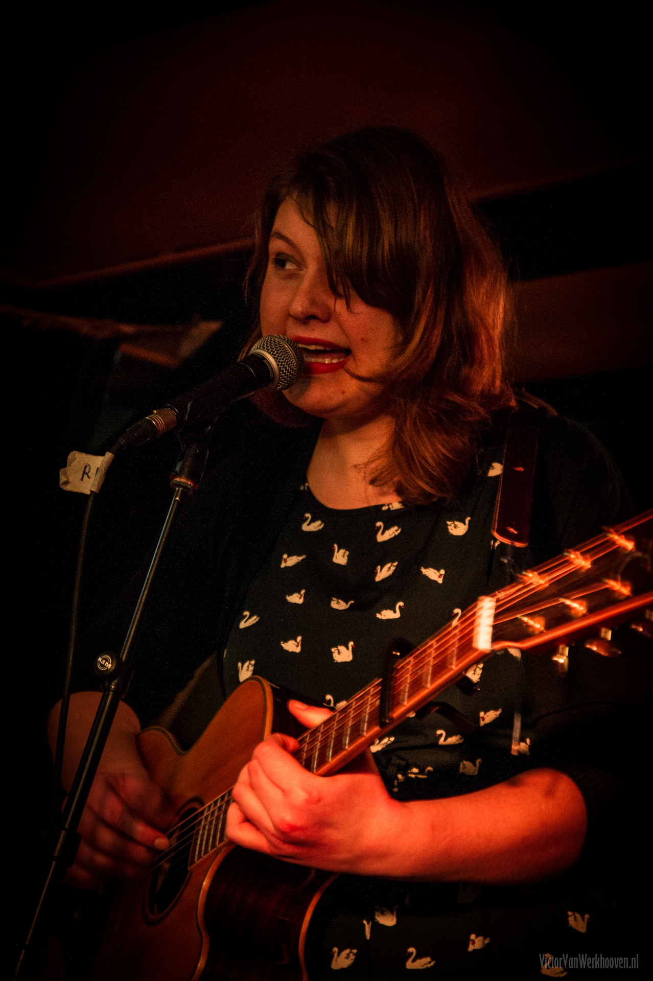 a woman playing guitar while singing into the microphone