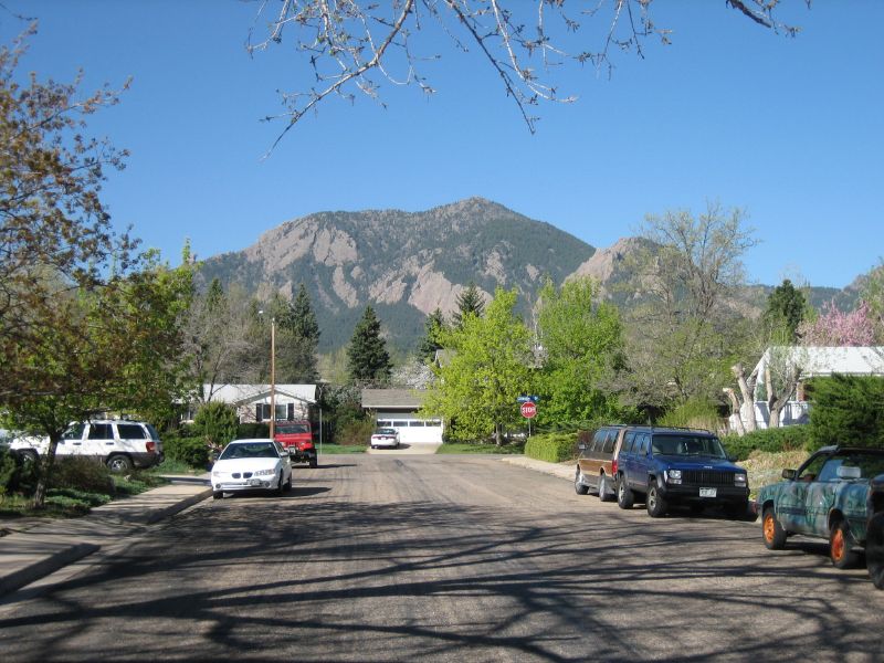 cars are parked at the end of an intersection with mountain in background